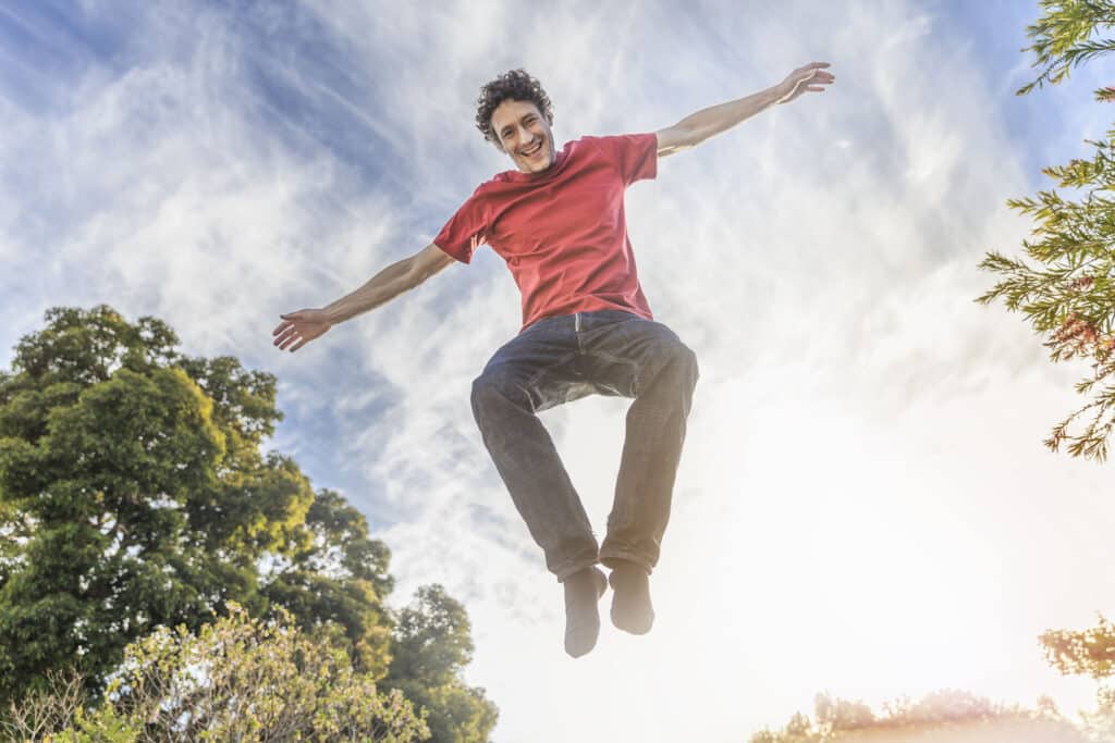 A photo of cheerful man jumping against sky. Full length of carefree male is enjoying in mid-air. He is in casuals.