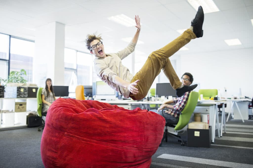 Businessman jumping into beanbag chair in office